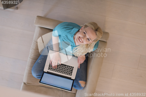 Image of Young woman using laptop at home top view