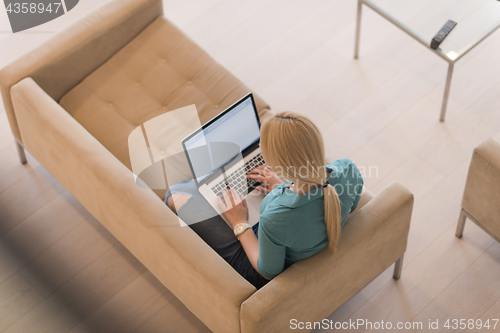 Image of Young woman using laptop at home