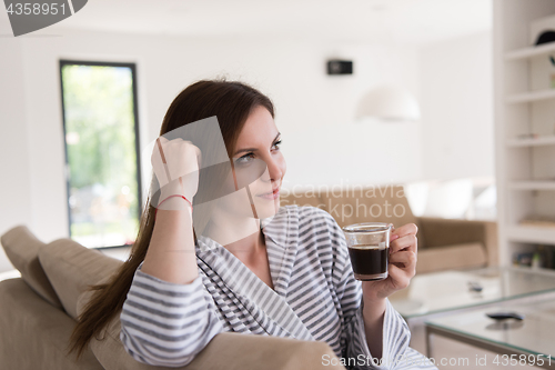 Image of young woman in a bathrobe enjoying morning coffee