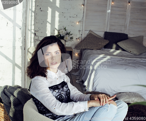 Image of young pretty brunette woman in her bedroom sitting at window, happy smiling lifestyle people concept 