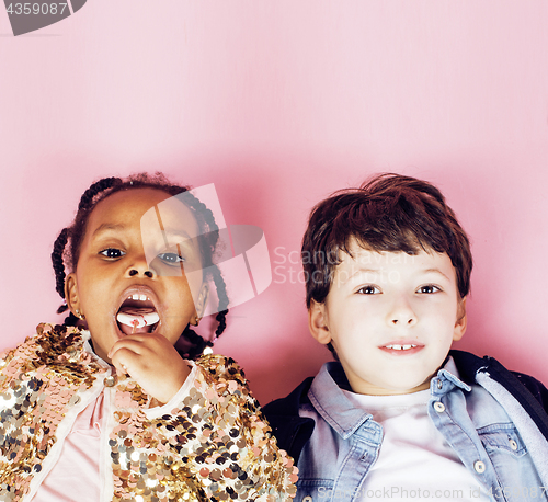 Image of lifestyle people concept: diverse nation children playing together, caucasian boy with african little girl holding candy happy smiling 