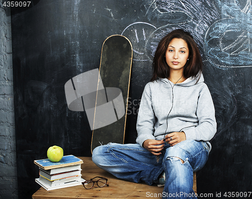 Image of young cute teenage girl in classroom at blackboard seating on ta