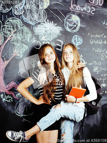 Image of back to school after summer vacations, two teen real girls in classroom with blackboard painted together, lifestyle people concept