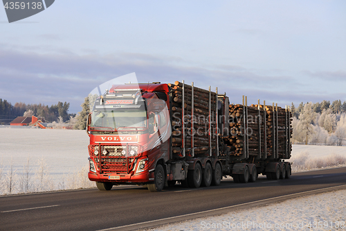 Image of Red Volvo Logging Truck Hauls Log Load in Winter