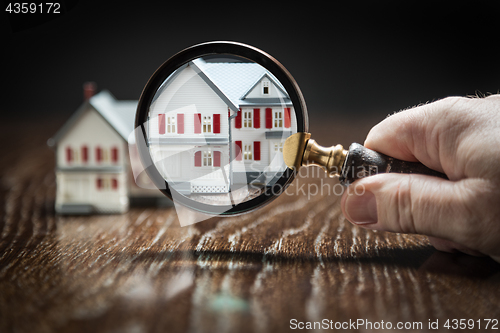 Image of Hand Holding Magnifying Glass Up To Model Home on Reflective Woo