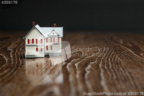 Image of Model Home on Reflective Wooden Surface.