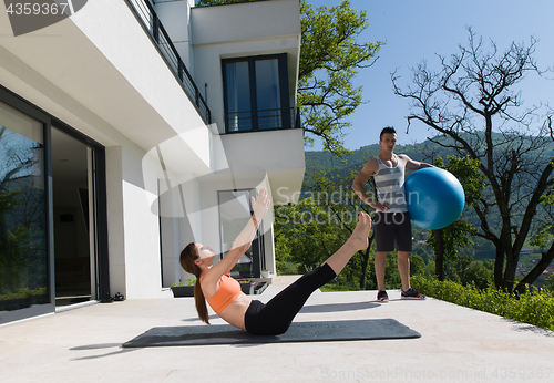 Image of woman and personal trainer doing exercise with pilates ball