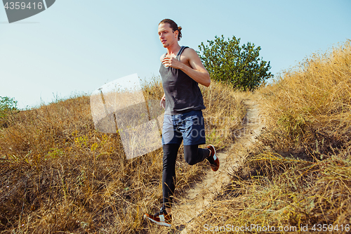Image of Running sport. Man runner sprinting outdoor in scenic nature. Fit muscular male athlete training trail running for marathon run.