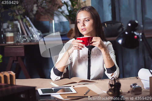 Image of Young beautiful woman working with cup of coffee