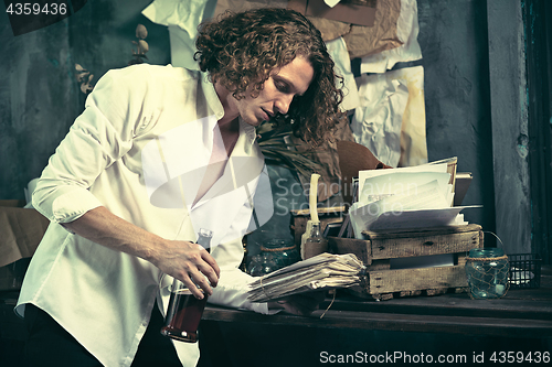 Image of Writer at work. Handsome young writer standing near the table and making up something in his mind