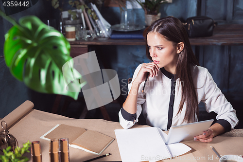 Image of Young beautiful woman working with cup of coffee
