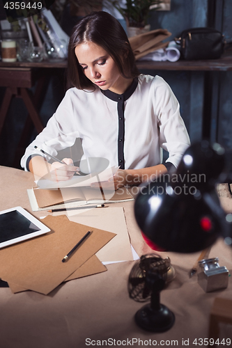 Image of Young beautiful woman working with cup of coffee