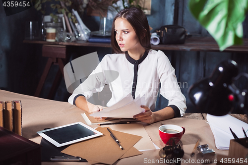 Image of Young beautiful woman working with cup of coffee