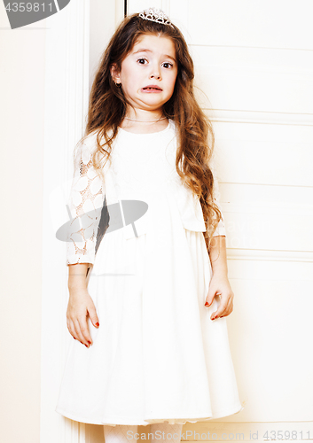 Image of little cute girl at home, opening door well-dressed in white dre