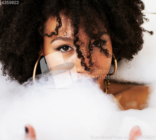 Image of young afro-american teen girl laying in bath with foam, wearing 