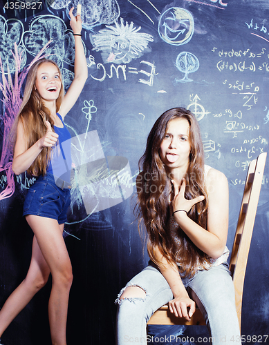 Image of back to school after summer vacations, two teen girls in classroom with blackboard painted