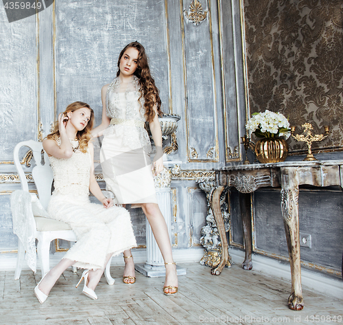 Image of two pretty twin sister blond curly hairstyle girl in luxury house interior together, rich young people concept 