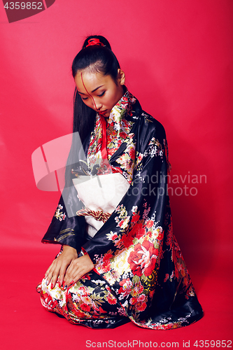 Image of young pretty geisha on red background posing in kimono, oriental people concept