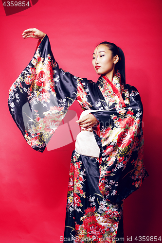 Image of young pretty geisha on red background posing in kimono, oriental people concept