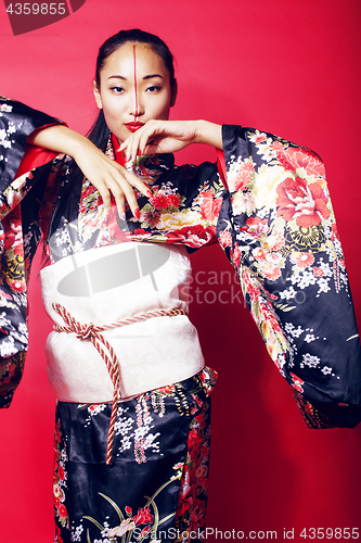 Image of young pretty geisha on red background posing in kimono, oriental people concept