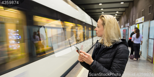 Image of Woman with a cell phone waiting for metro.