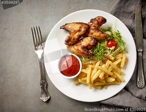 Image of Plate of fried potatoes and chicken wings