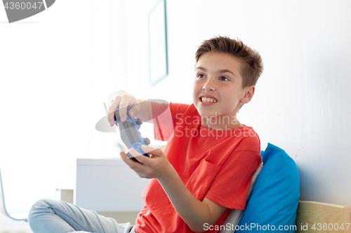 Image of happy boy with gamepad playing video game at home