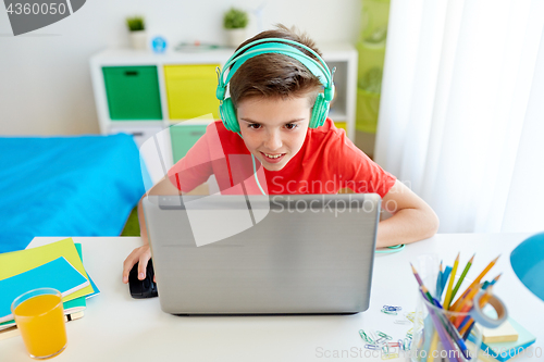 Image of boy in headphones playing video game on laptop