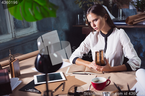 Image of Young beautiful woman working with cup of coffee