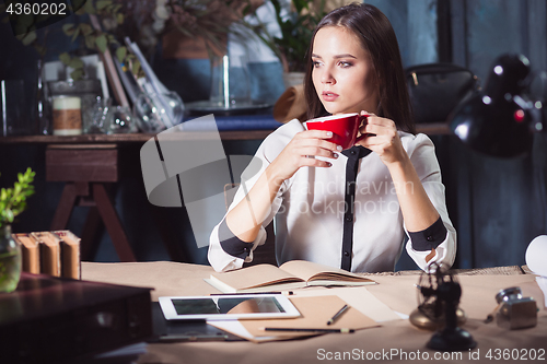 Image of Young beautiful woman working with cup of coffee