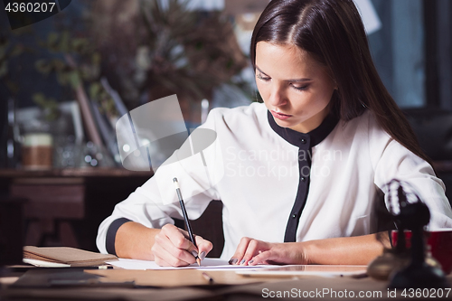 Image of Young beautiful woman working with cup of coffee