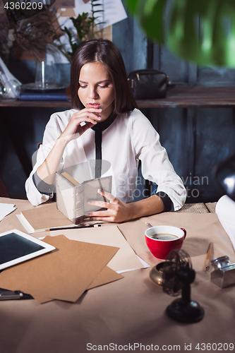 Image of Young beautiful woman working with cup of coffee