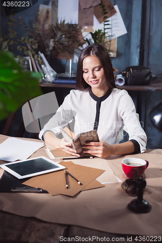 Image of Young beautiful woman working with cup of coffee