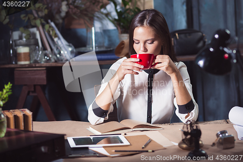 Image of Young beautiful woman working with cup of coffee