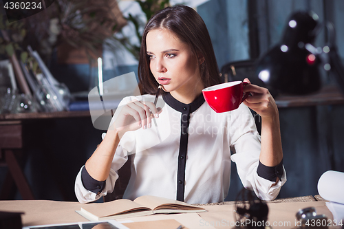 Image of Young beautiful woman working with cup of coffee