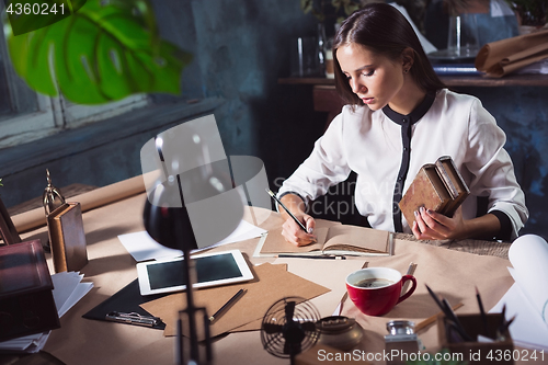 Image of Young beautiful woman working with cup of coffee