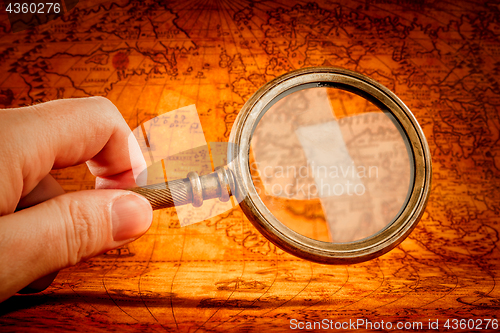 Image of Vintage magnifying glass lies on an ancient world map