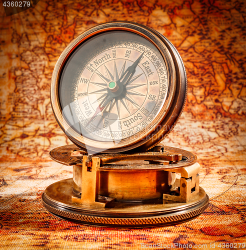 Image of Vintage compass lies on an ancient world map.