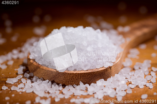 Image of Sea salt crystals closeup in wooden spoon on a kitchen table.