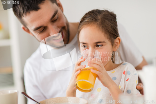 Image of happy girl with father drinking juice at home