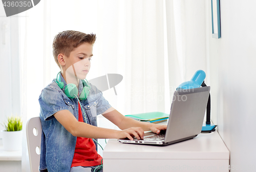 Image of boy with headphones typing on laptop at home