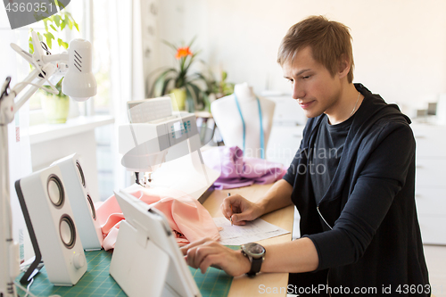 Image of fashion designer with tablet pc working at studio