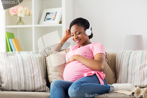 Image of pregnant woman in headphones at home