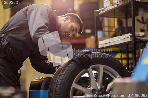 Image of auto mechanic balancing car wheel at workshop