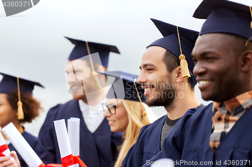 Image of happy students in mortar boards with diplomas