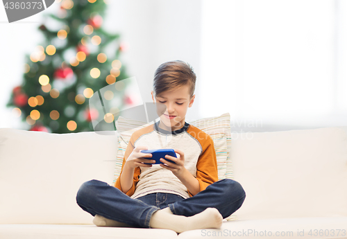 Image of boy playing on smartphone at home at christmas