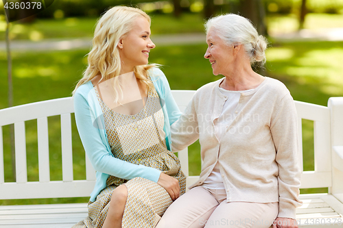 Image of daughter with senior mother hugging on park bench