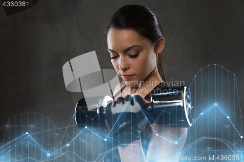 Image of young woman flexing muscles with dumbbells in gym