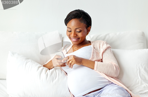 Image of happy pregnant woman with smartphone at home