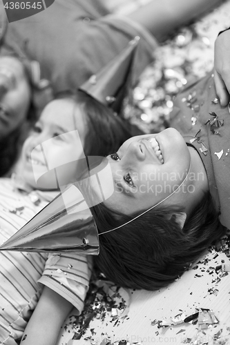 Image of kids  blowing confetti while lying on the floor